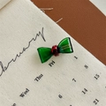 Detail einer grünen handgemachten Schleifen-Haarspange mit roter Perle auf Kalender - Grün