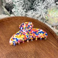 Close-up of a colorful terrazzo pattern hair claw clip on a rustic wooden tray - Graffiti Palette