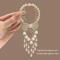 Détail d'une pince à cheveux dorée avec glands muguet et un nœud en cristal brillant - Nœud Muguet Gland