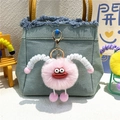 Pink plush monster keychain with red lips and metal clip shown as a backpack charm - Pink