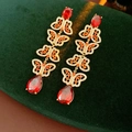 Detail von Vintage-Schmetterlings-Ohrringen mit rotem Zirkon auf dunkelgrünem Samt - Gold mit Rot (Silberstift)