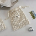Close-up of white mesh lace storage bag with delicate daisy floral embroidery and drawstring - Daisy Apricot Small
