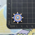 Macro detail of a 2.5cm blue resin ship helm charm for DIY crafts and accessories - Ship Wheel