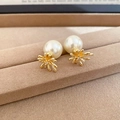 Macro detail of elegant pearl stud earrings with golden fireworks metal setting and zircons - Gold