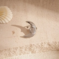 Macro shot of silver crescent moon face clip-on earring on textured stone with shell decor - Clip Earring - Silver Moon Face