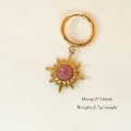 Makro-Detail von 14K vergoldeten Sonnenohrringen mit rosa Edelstein auf beigem Stoff - Rhodochrosit Achtzackiger Stern