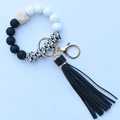 Close-up of silicone beaded keychain bracelet with wood bead and black tassel detail - Black and White Leopard Print
