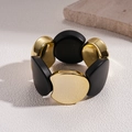 Close-up van vintage acryl elastische armband met gepolijste gouden en zwarte kralen - Goud/Zwart