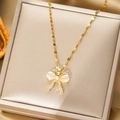 Champagne gold bow necklace featuring white cat-eye stones and pearl accents in a jewelry box - Gold Bow Style