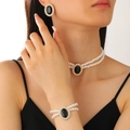 Detail einer zweilagigen Perlenkette und schwarzen Edelsteinohrringen am Modell - Gold Schwarz