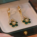 Detailed macro view of golden flower earrings with green crystals and a central pearl - Snowflake Christmas Green Flower