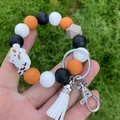 Silicone bead wristlet keychain with cartoon cow pendant and white tassel on grass - Orange