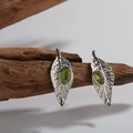 Dettaglio macro di orecchini in argento a foglia con gemma verde su legno - Orecchini / Argento / Peridoto