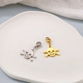 Detail of silver and gold skull crossbones charms with lobster clasps on ceramic plate - Skull Style 2
