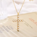 Collana con ciondolo a croce placcata oro e perle bianche su sfondo di libro francese - Stile 23373