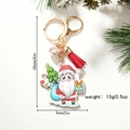 Cute Santa Claus Christmas keychain with red tassel and acrylic tag on a festive backdrop - Santa Carrying Gifts