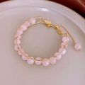 Vista macro del bracciale fatto a mano in quarzo rosa con filo dorato e chiusura a moschettone - Braccialetto con charm farfalla rosa