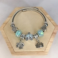 Detail of twisted metal bangle with elephant, crown pendants and blue glass beads - Lake Blue