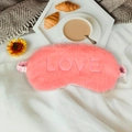 Pink faux rabbit fur sleep eye mask with LOVE embroidery and elastic strap on white bed - LOVE Embroidery / Carmine