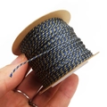 Detailed view of 1mm blue and gold twisted cord on a paper spool for DIY jewelry - Navy Blue