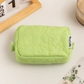 Close-up of mint green quilted floral makeup bag with a minimalist woven label - Light Green