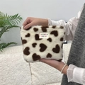 Detail of plush heart-patterned makeup bag held by hand with colorful woven label - White Hearts
