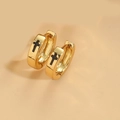 Macro shot of gold hoop earrings with black cross patterns on a clean beige surface - Black