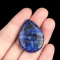 Water drop blue natural stone pendant with gold pyrite flecks held in hand - Lapis Lazuli