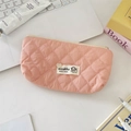 Nahaufnahme der rosa gesteppten Kosmetiktasche mit Welpenlogo auf weißem Schreibtisch - Nute Rosa