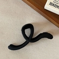 Pince à cheveux noire mate en forme d'infini sur fond beige rustique avec décorations - Style Torsadé Noir Mat