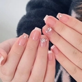 Close-up of nude press-on nails with white French tips and crystal heart rhinestones - By1579 Masato Seichi / Glue Type