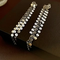 Dettaglio macro di orecchini a clip con nappe di paillettes su trama in pelle scura - Clip per orecchie con nappe e paillettes / Argento