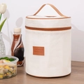 Geïsoleerde beige canvas lunchtas met bruin leren label en rits in een huiselijke sfeer - Cilindervorm / 18.5*18.5*23cm