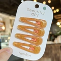 Detailed view of four orange glitter teardrop hair clips on a white branded card - Orange