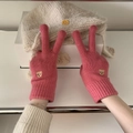 Close-up of pink knitted gloves with cute bear embroidery shown on a white gift box - Rose Pink