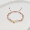 Detailed shot of handmade woven bracelet with initial S pendant and white pearl detail - Letter S
