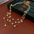 Détail d'un collier doré multicouche avec pendentifs en zircone ronde sur support - Or-Blanc