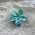 Detailansicht der blauen Marmor-Blumen-Haarklammer auf weichem weißem Papier - Blau