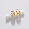 Minimalist gold geometric hoop earrings with polished metallic finish on white fabric - Gold