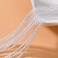 Macro shot of 2mm faceted crystal beads cascading from a ceramic bowl for DIY jewelry - Clear White