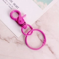 Vibrant pink painted metal lobster clasp with round key ring on marble background - Rose Red