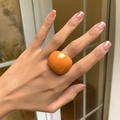 Close-up of a large orange resin geometric square ring worn on a finger - Orange