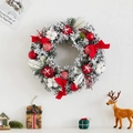 Frosted Christmas wreath with red bow, ornaments and snowy pine needles on white wall - Snow-flocked Wreath