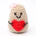 Close-up of handmade crochet potato toy with pink bow and heart decor on white background - Khaki Potato Blush Bow Black Thread Heart Shape