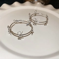 Silver bow hoop earrings with four delicate charms on a decorative white tray - Silver-Bow