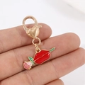 Pink rose and red lips charm pendant with golden heart lobster clasp held by hand - Red Lips Rose