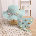 Detail of mint green straw sun hat and matching crossbody bag with colorful pom-poms - Blue Hat + Bag