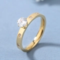 Anillo minimalista de acero de titanio dorado con gran circonita redonda y piedras laterales - US 7 / Dorado