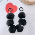 Dettaglio di portachiavi con pompon di peluche nero e perle su sfondo carta - Nero