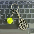 Miniature yellow tennis ball and bronze racket keychain charm displayed on a keyboard - 4.8cm*3.8cm / New Edition Metal Tennis Green